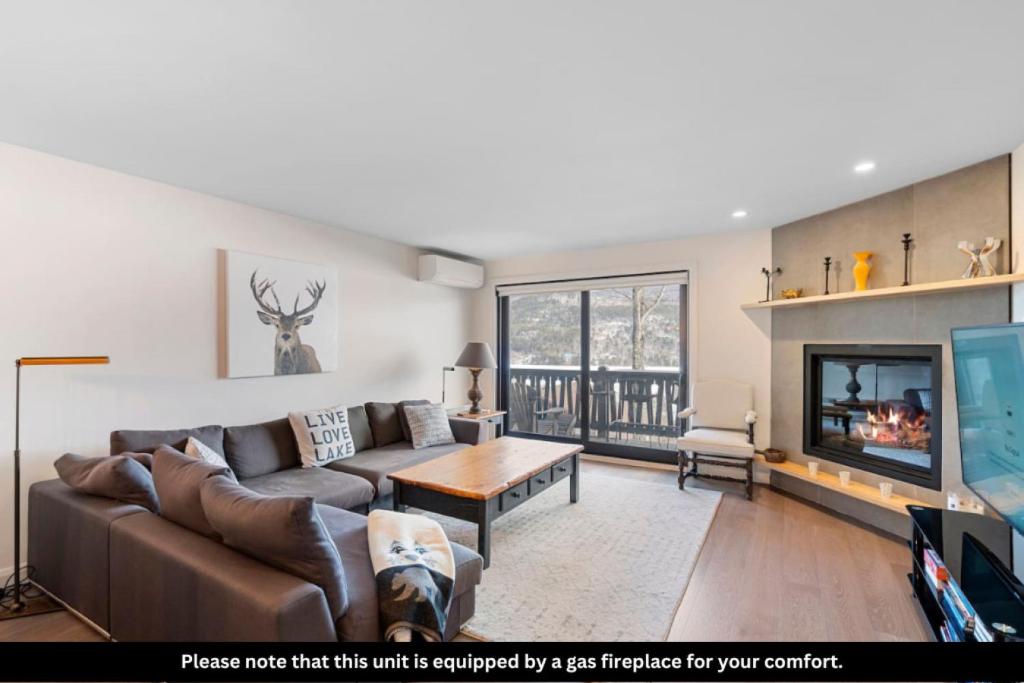 a living room with a couch and a fireplace at Spacious Condo with Lake and Mountain View in Mont-Tremblant