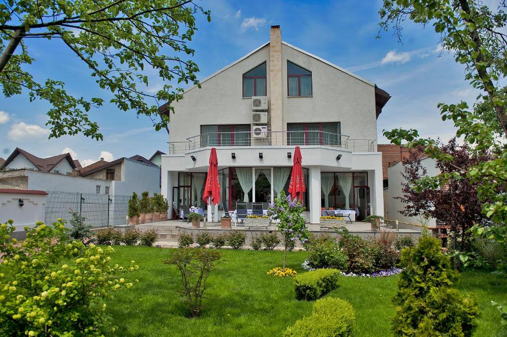 a large white house with red umbrellas in the yard at Casa Jasmine in Braşov