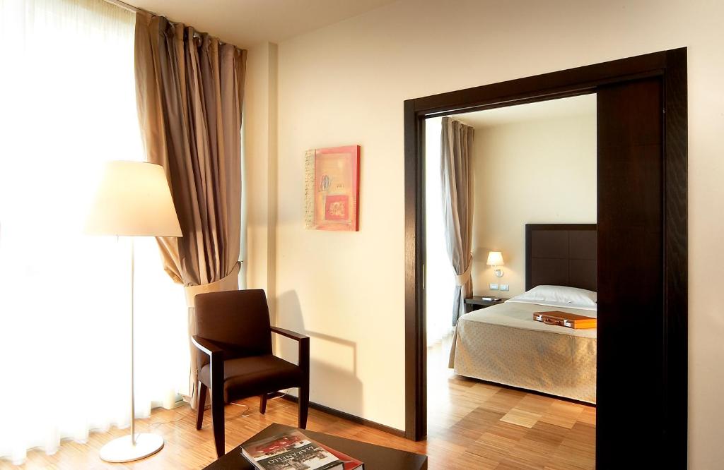 una camera da letto con specchio, letto e sedia di Hotel Real Fini Baia Del Re a San Donnino della Nizzola