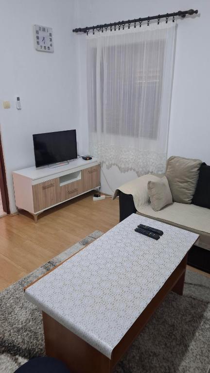 a living room with a table and a couch and a tv at Apartman Jezero in Trebinje