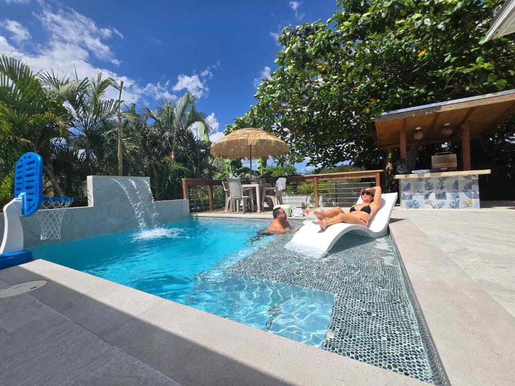 two people sitting in chairs in a swimming pool at Casita Almendro-Apartment With Heated Pool in San Germán