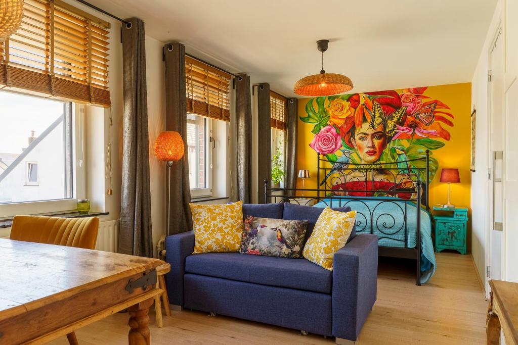 a living room with a blue couch and a painting at Droom op de Vijlenberg in Vijlen