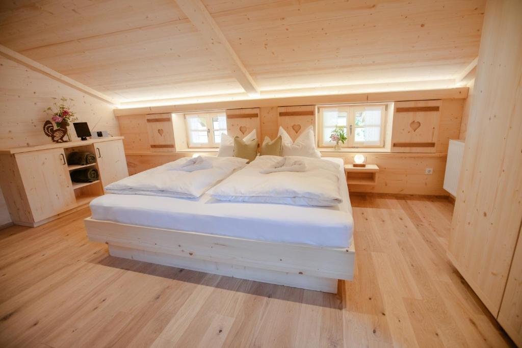 ein Schlafzimmer mit einem weißen Bett in einer Hütte in der Unterkunft Pension Gerstenbrand in Fischbachau