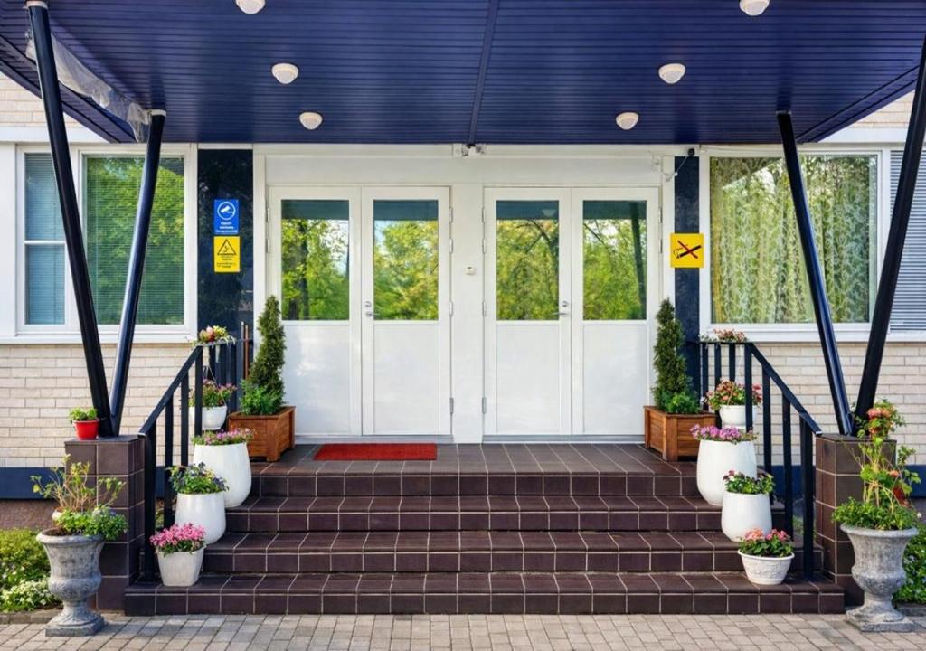 a front door of a house with potted plants at Hotel Ilomantsi North Star in Ilomantsi
