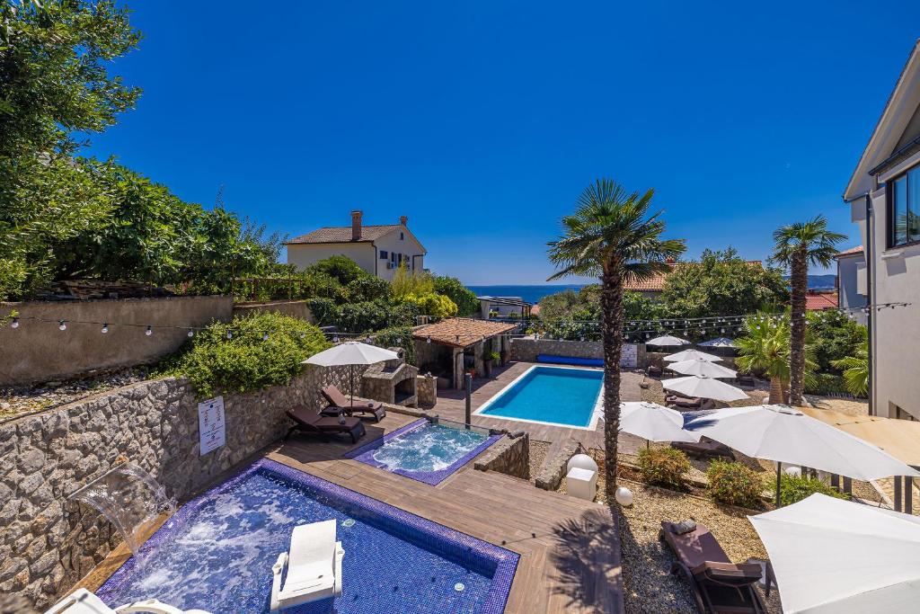 a swimming pool with umbrellas and a resort at Villa Palma Krk in Krk