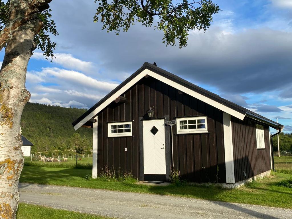 a brown and white barn with a white door at Tørresvangen in Tynset