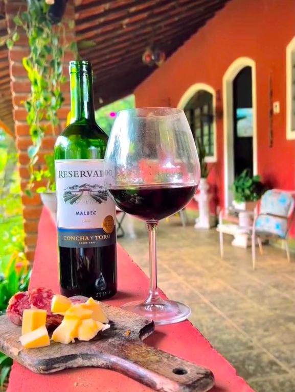 a glass of wine next to a bottle of wine at Chale da Pousada Curió in Ibiúna