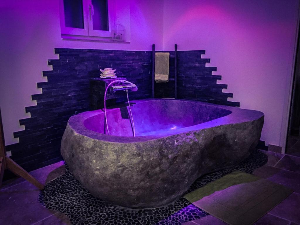 d'une grande baignoire en pierre dans une chambre avec éclairage violet. dans l'établissement Au Charme de Pépiole, à Six-Fours-les-Plages
