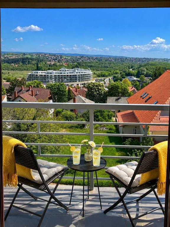 a balcony with two chairs and a table with drinks on it at Savelij apartament in Hévíz
