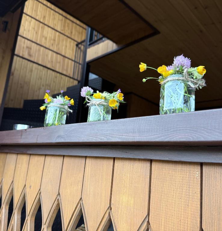 three vases filled with flowers sitting on a table at Sky Tusheti in Omalo