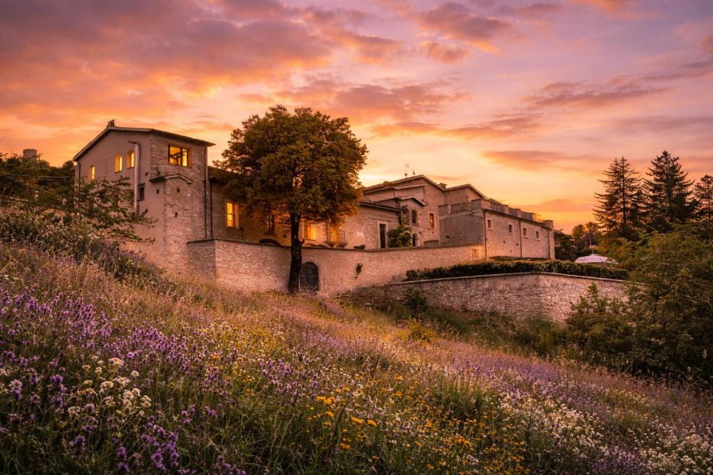 a castle on a hill with a field of flowers at B&B Palazzo Agrippa in Bominaco