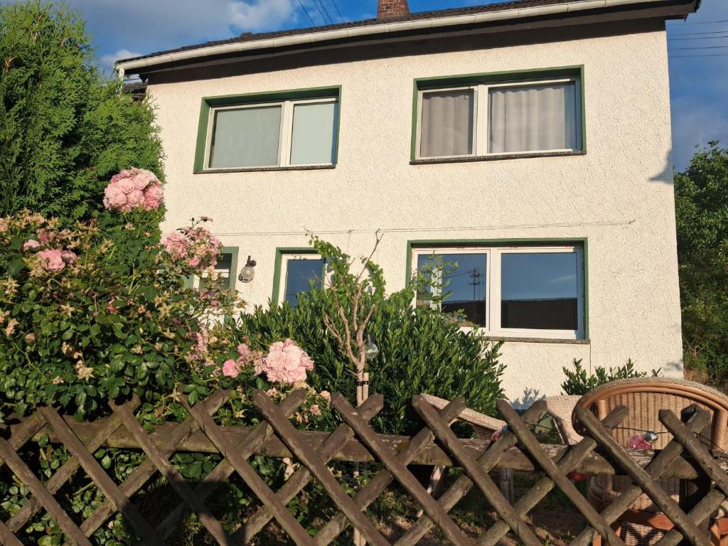 a house behind a wooden fence with pink flowers at Ferienhaus am Ring in Wimbach
