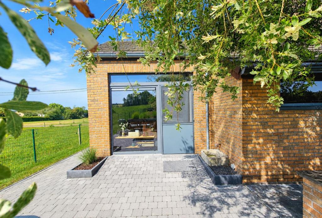 a brick house with a glass door at Gîte La Petite Villette in Fronville