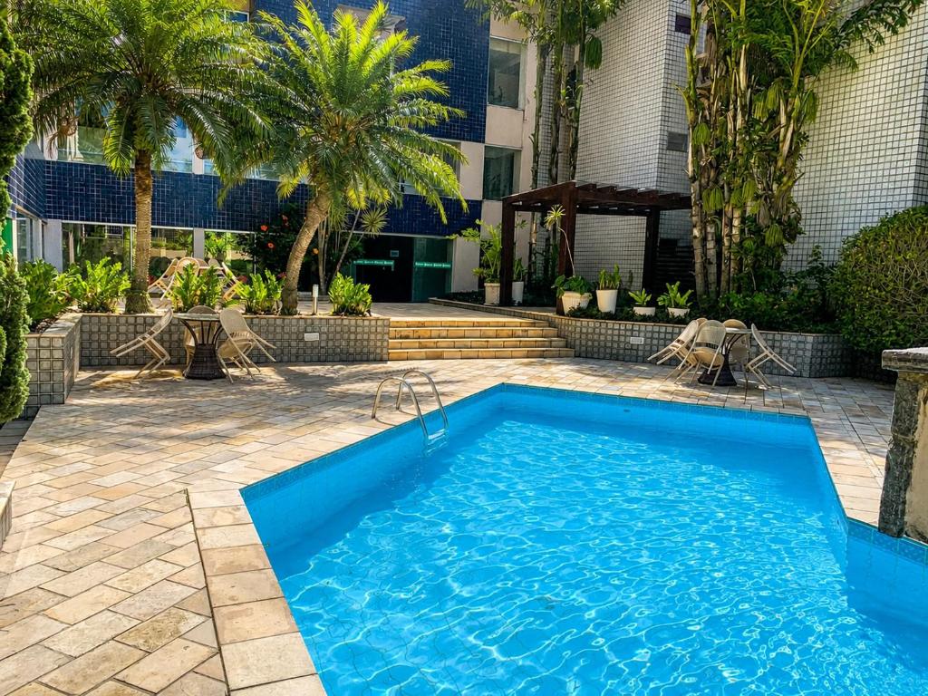 a swimming pool in a yard with palm trees at Caruaru Pallace Hotel in Caruaru
