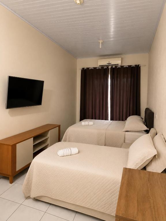 a hotel room with two beds and a flat screen tv at Loft Farol in Pântano Grande