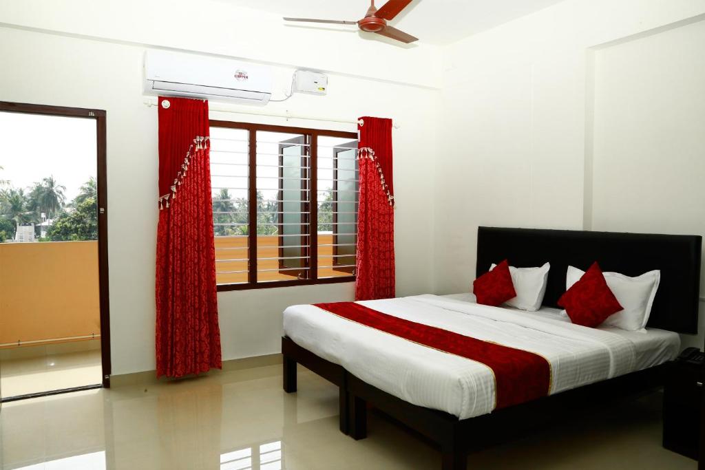 a bedroom with a bed with red curtains and a window at Hotel O Technopark Formerly Le Frank in Trivandrum