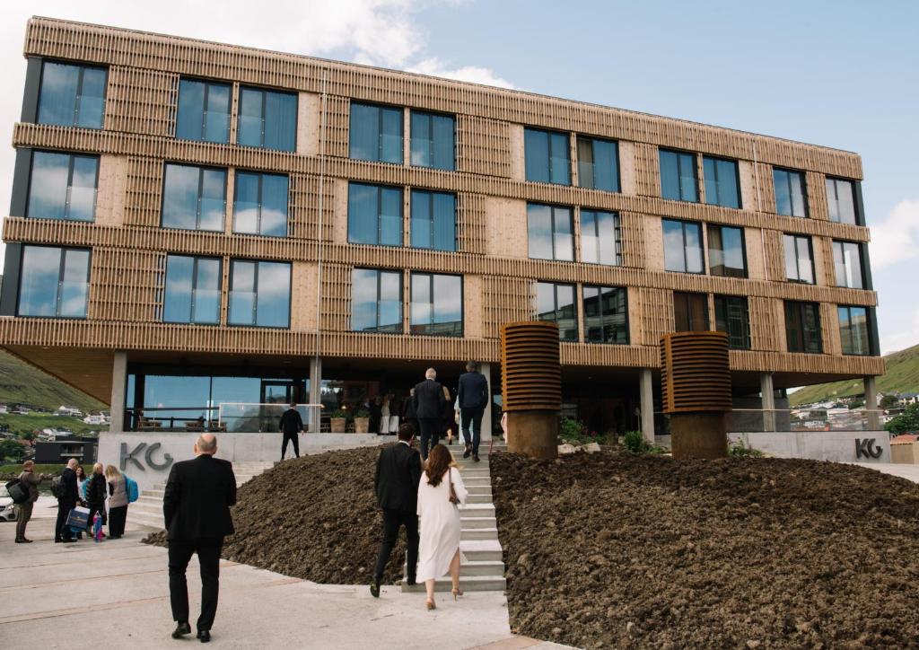 Eine Gruppe von Menschen geht vor einem Gebäude entlang in der Unterkunft KG Hotel in Klaksvík