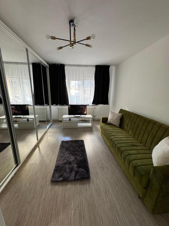 a living room with a green couch and some windows at Nova Stay Craiova in Craiova
