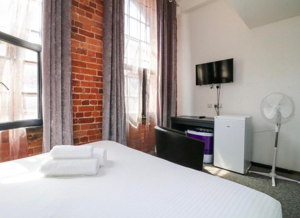 a bedroom with a white bed and a brick wall at Kick back relax stylish space in Nottingham