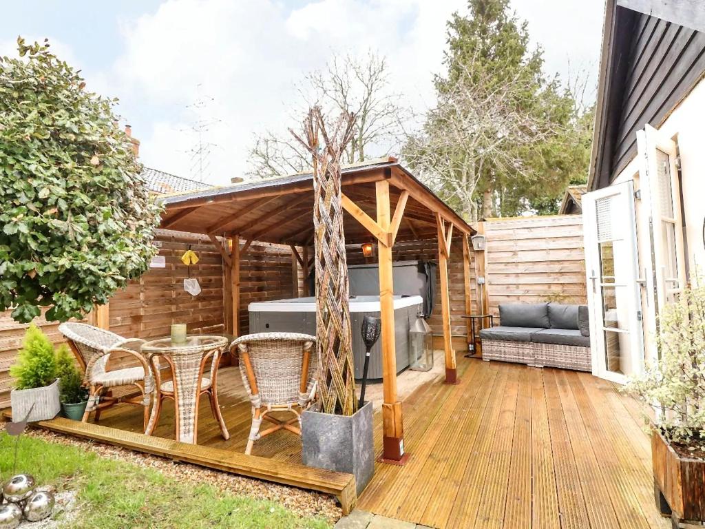 a deck with a hot tub and a table and chairs at Tiny Home with Hot Tub in Roydon