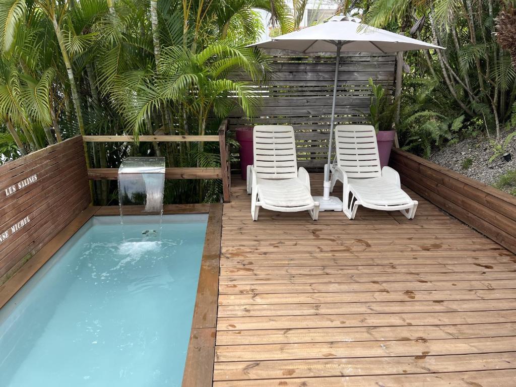 two chairs and an umbrella next to a swimming pool at Cap Lodge in Le Marin