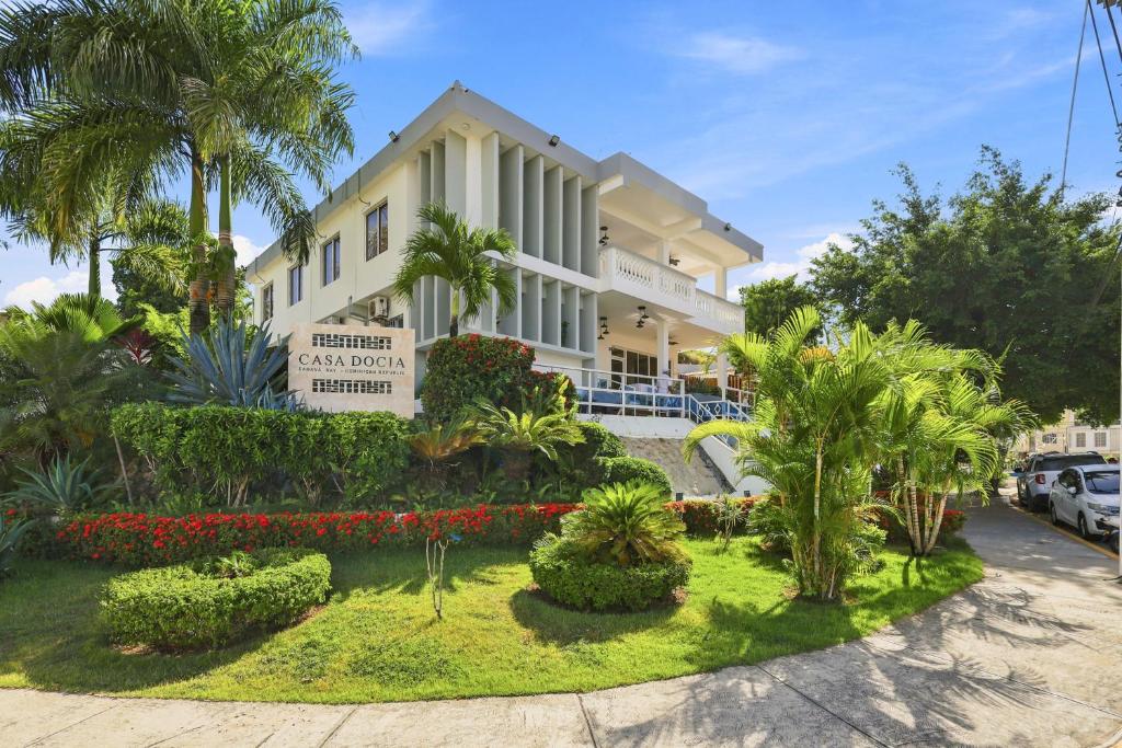 a large white building with palm trees and bushes at Casa Docia Hotel in Santa Bárbara de Samaná