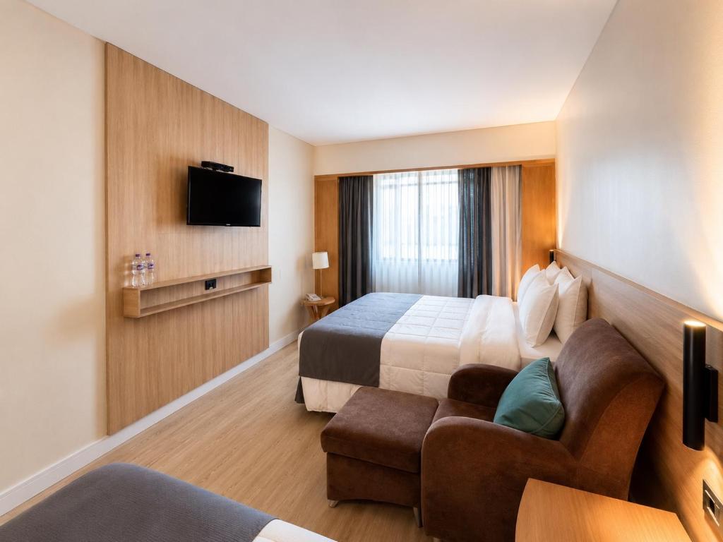 a hotel room with a bed and a couch at Hotel & Residence Sol Alphaville Flat in Barueri