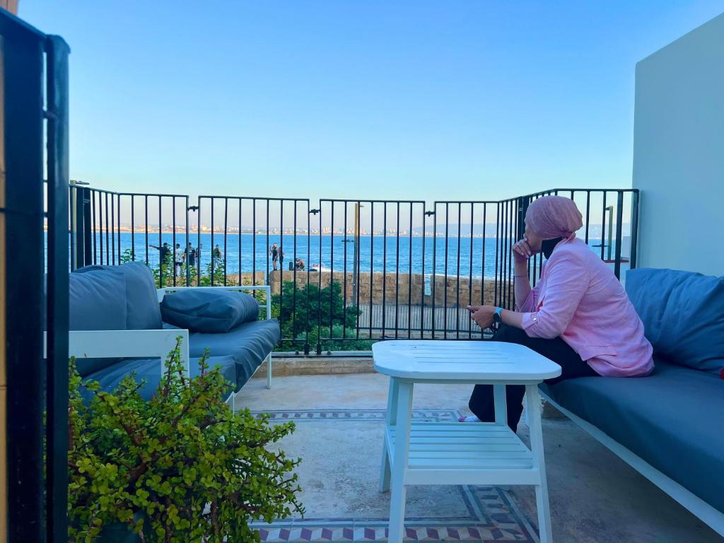 a woman sitting on a couch looking at her cell phone at Siwar Boutique Suites in Acre