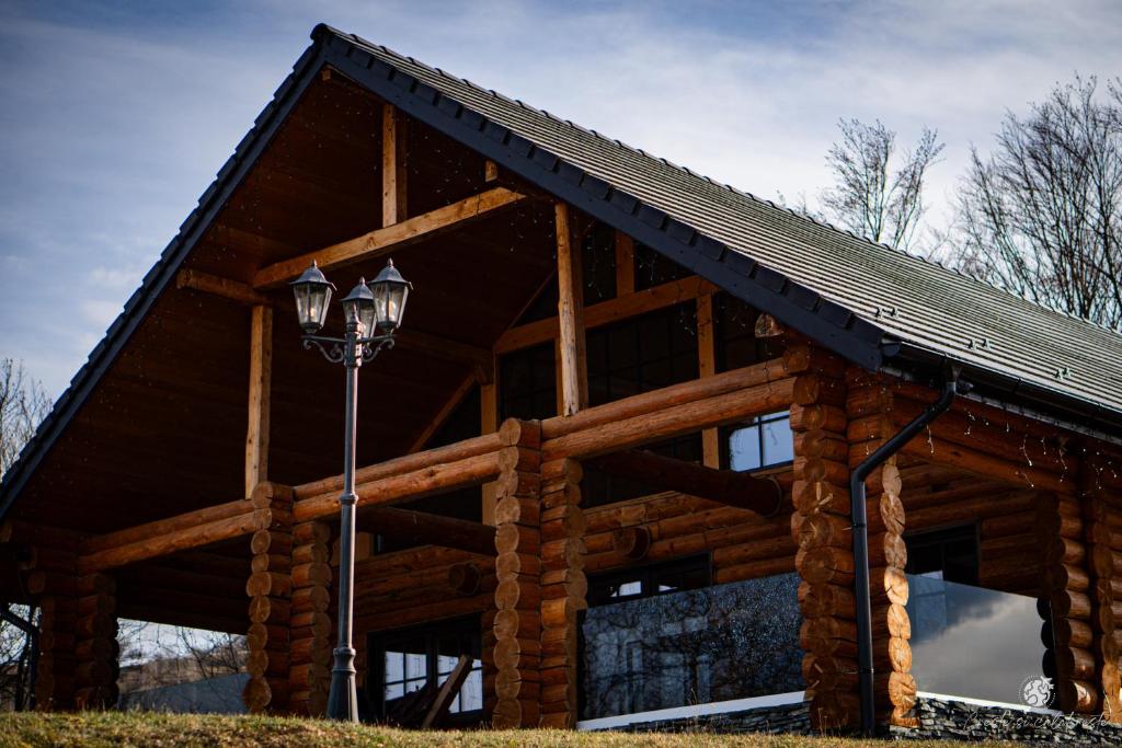 a log cabin with a street light in front of it at Amber Hills Romania in Braşov