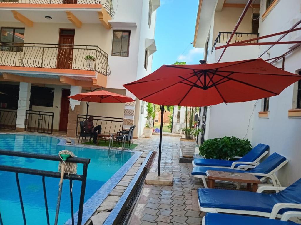 a pool with chairs and an umbrella next to a building at Silent breeze home in Mombasa