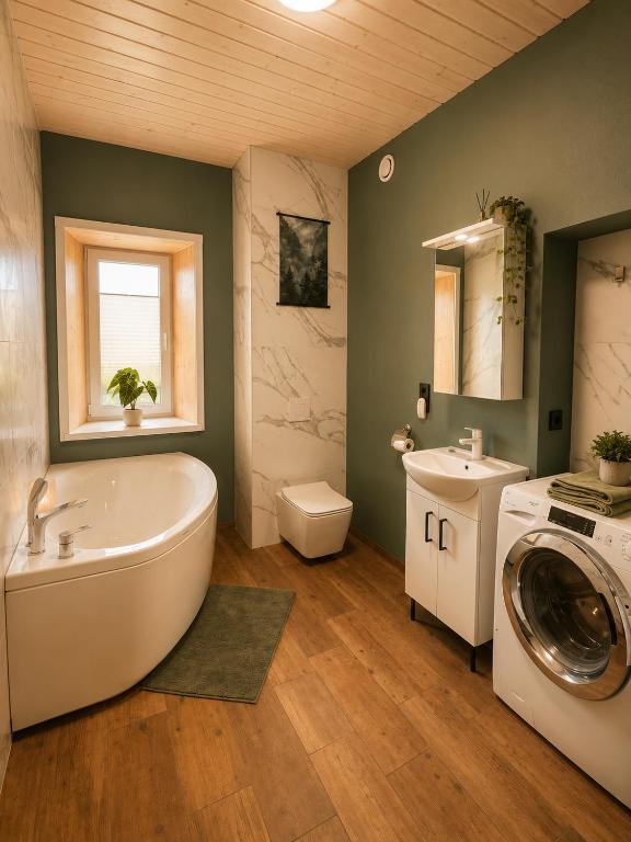 a bathroom with a tub and a sink and a washing machine at Ulila guesthouse in Ulila