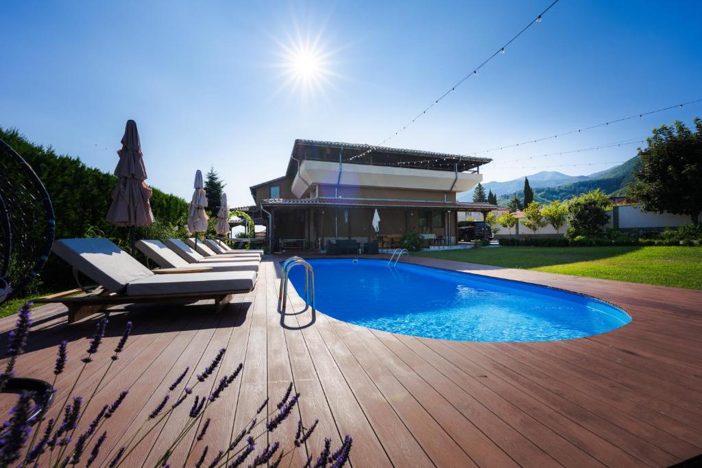 a swimming pool on a wooden deck next to a house at Villa Manevi in Yavornitsa