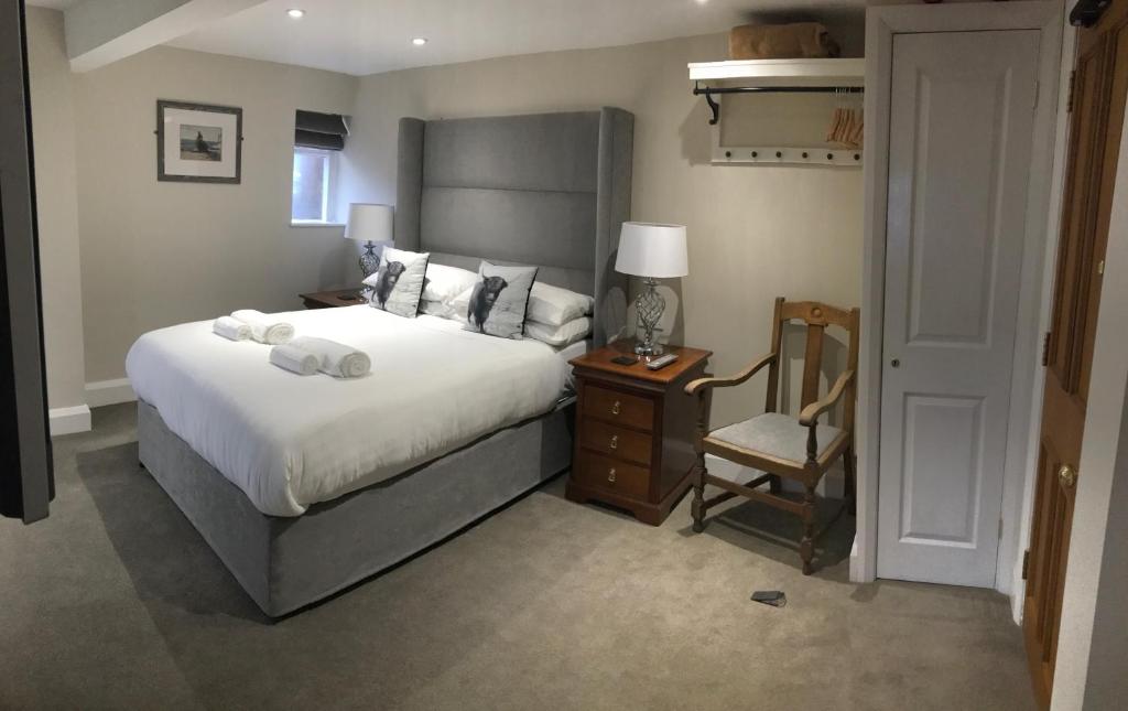a bedroom with a large bed and a chair at The Bulls Head in Swadlincote