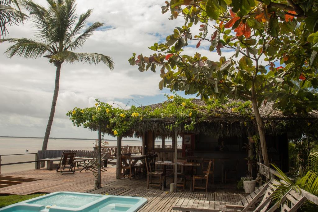 a wooden deck with a table and chairs on the beach at Pousada Delta Chalés in Tutóia