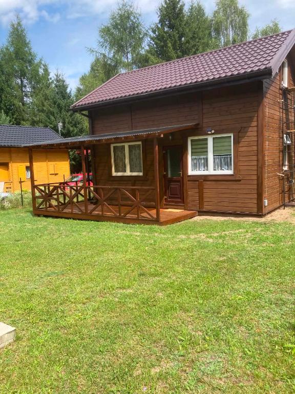 a log home with a deck and a yard at Dolina Nataci in Nidzica