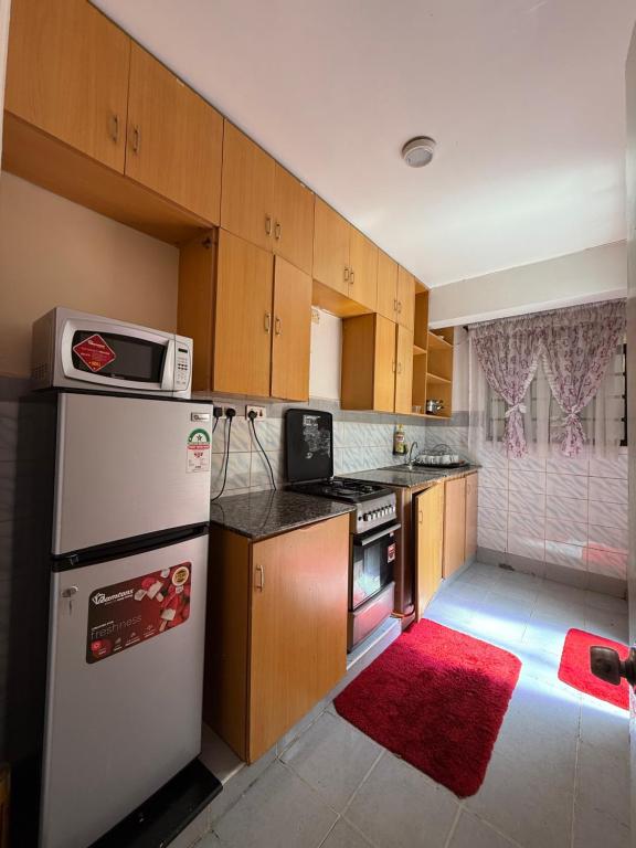 a kitchen with a white refrigerator and a red rug at Tulia Retreats in Syokimau