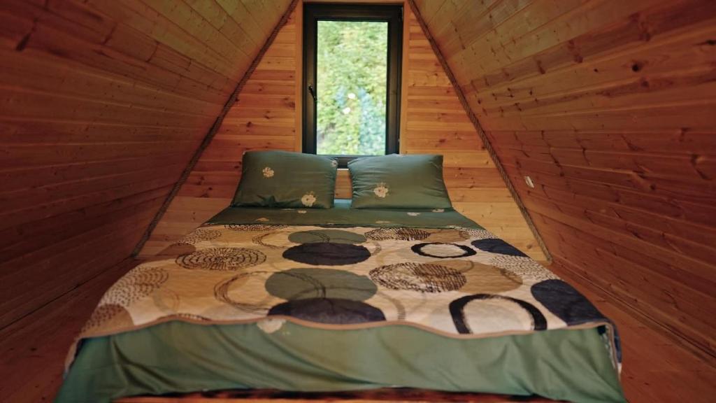 a bed in a log cabin with a window at Kesane Cottages in Racha in Oni