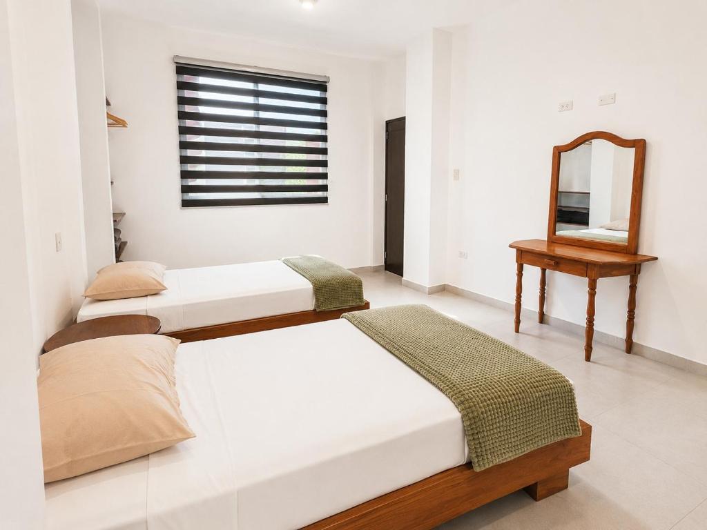 two beds in a white room with a mirror at Galápagos Downtown Suite in Puerto Ayora