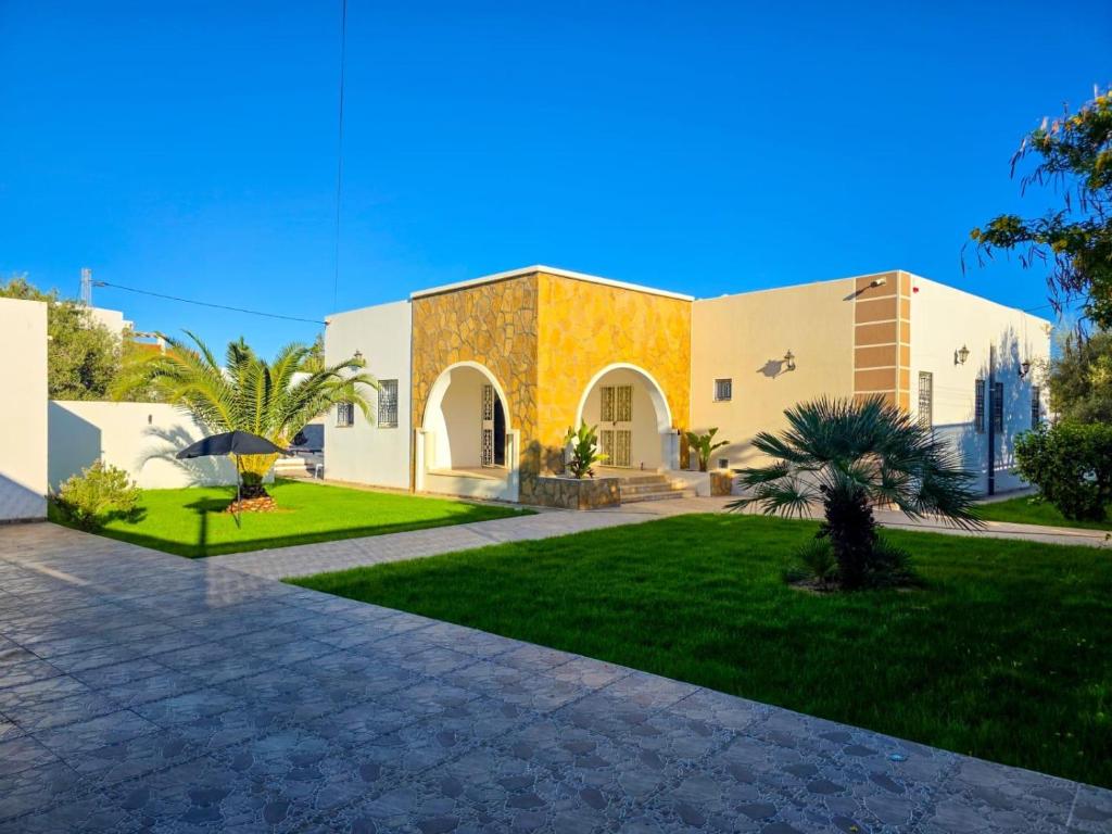 a house with a courtyard with a grass yard at Villa Safiya in Djerba