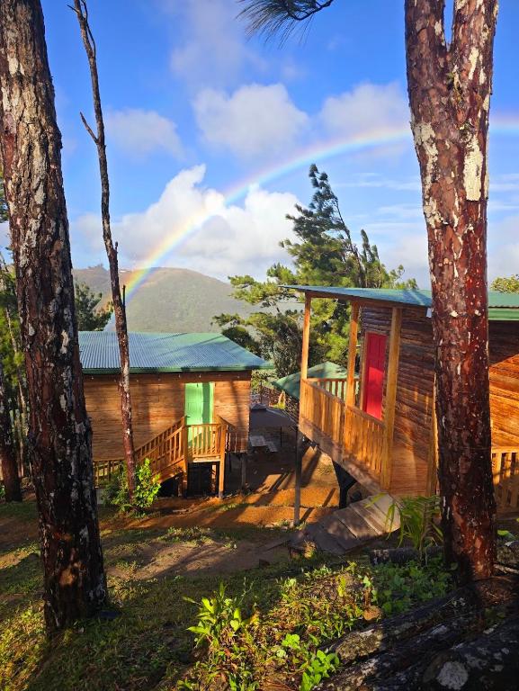 a wooden house with a rainbow in the background at Altos del Dragón in Valle de Anton