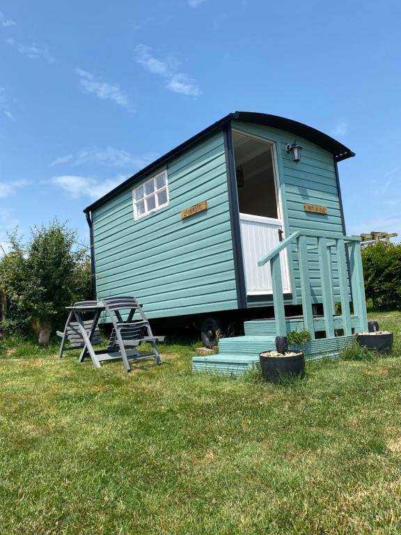 a green tiny house with a picnic table in the grass at Hut 4 Ewe glamping pod with shared facilities in Bideford