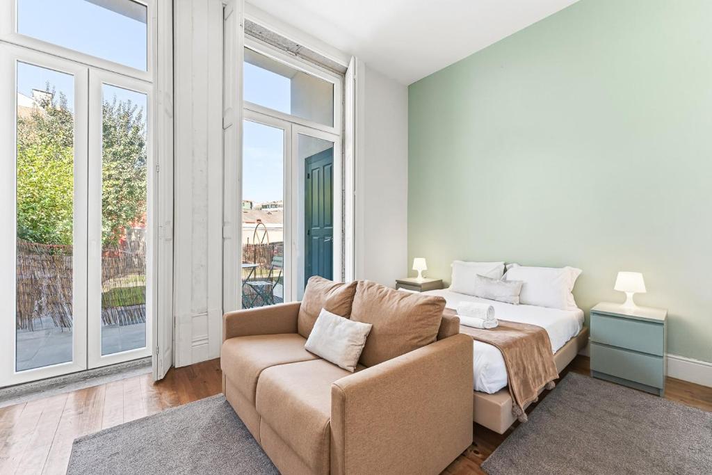 a bedroom with a bed and a couch and a window at GuestReady - Porto Home GuestHouse in Porto
