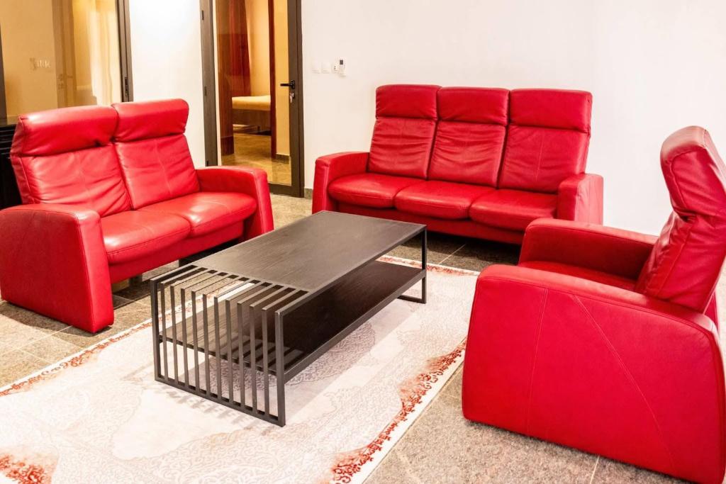a living room with red chairs and a coffee table at Villas HouN Assinie in Mafia