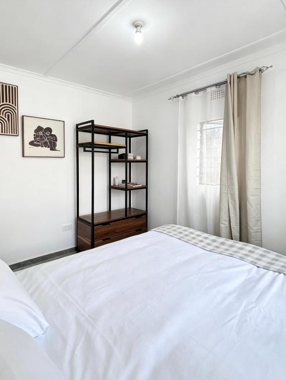 a bedroom with a white bed and a window at The Tiny House - Solwezi in Solwezi