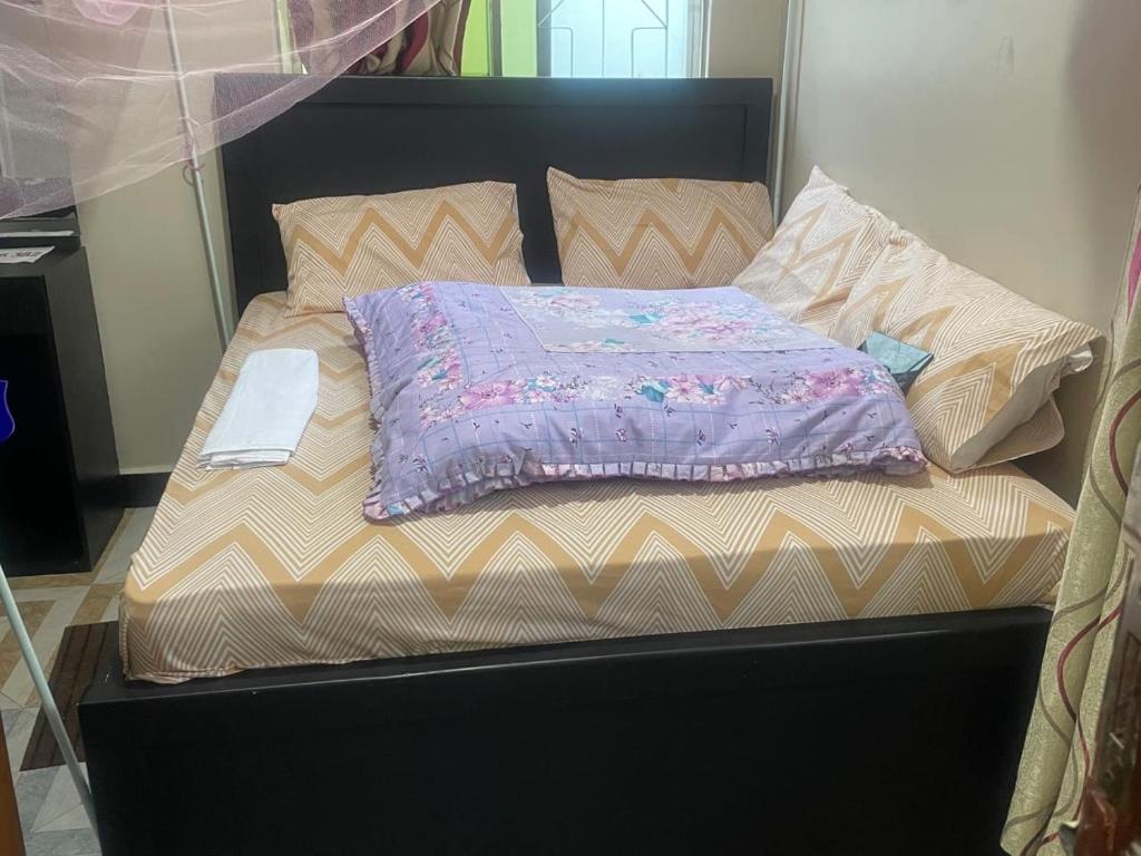 a bed with a purple comforter on top of it at The John's Park in Mwanza