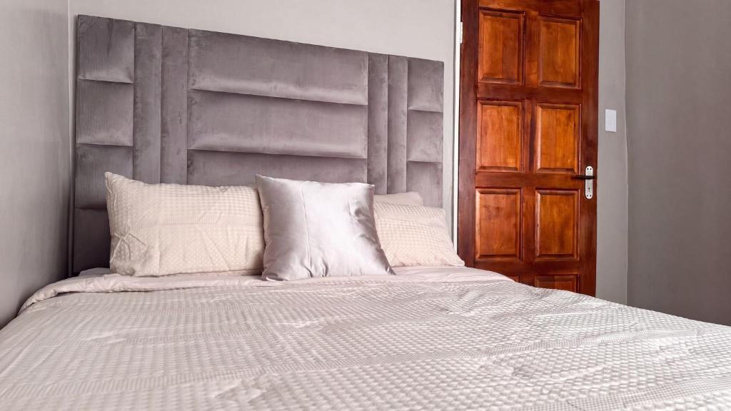 a bed with a gray headboard and white pillows at SAOB Property- South A in Germiston