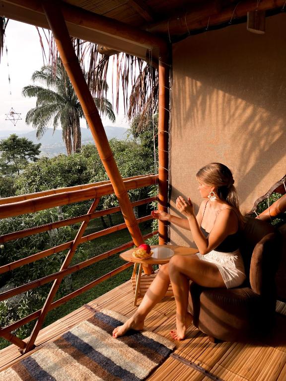 a woman sitting on the porch of a house at Cultivarte in Anapoima