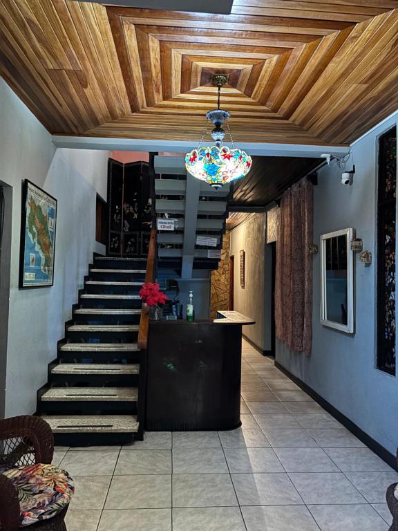 a hallway with stairs and a ceiling with a chandelier at Charly's Place in Alajuela