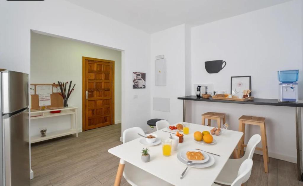 a kitchen with a white table and chairs with food on it at Habitaciones IFAE in Alcalá