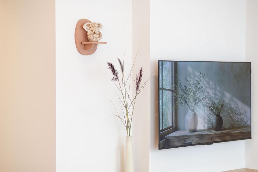 a tv on a wall with vases and a window at Unique apartment with all comforts and sauna in Otepää